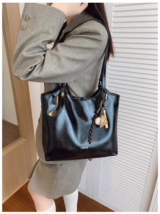 Detail of black glossy leather tote bag with baseball charms and Fashion text print