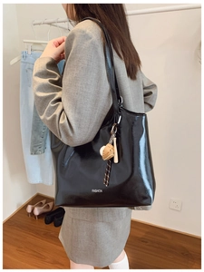 Detail showing glossy black tote bag with fashion print and baseball keychain accessory