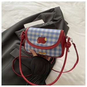 Détail du tissu à carreaux bleus et bordure en cuir rouge sur mini sac de selle