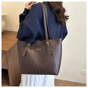 Deep brown leather tote bag with vintage texture and metal buckle on slender shoulder strap