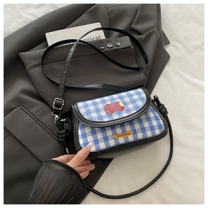 Détail du mini sac selle à carreaux avec broderie pomme sur un blazer gris