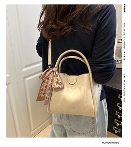 Detail of beige bucket bag with elegant brown checkered silk scarf on the top handle