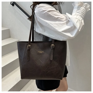 Detail of dark brown leather tote bag showing fine straps and metal buckle on stairs