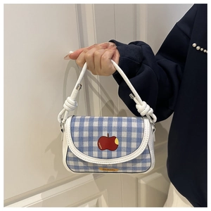 Détail du mini sac à carreaux bleus avec broderie pomme et poignée en cuir blanc noué