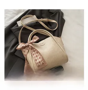 Detailed view of beige bucket bag size compared with smartphone and silk scarf detail