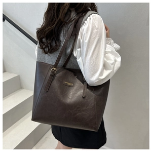 Detail of dark brown tote bag with retro oil wax texture and metal buckle on the shoulder strap
