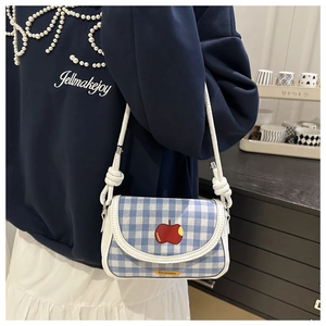 Détail du sac bandoulière à carreaux bleus avec broderie pomme rouge et bandoulière nouée
