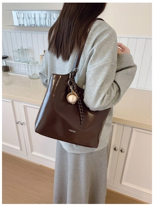 Detail of a deep brown glossy tote bag with Fashion lettering and baseball charm