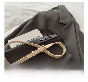 Detailed shot of beige embossed leather shoulder strap with a golden metal buckle