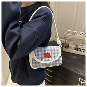 Détail du sac à carreaux bleus avec broderie pomme rouge et bandoulière blanche fine