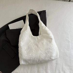 Sac hobo chic en toile beige avec broderie florale sur fond de blazer noir élégant