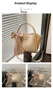 Detail of beige PU leather bucket bag with silk scarf knot and gold logo accent