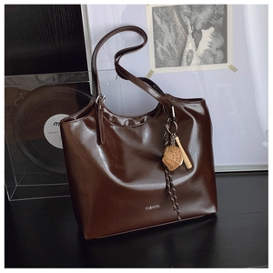 Deep brown tote bag detail with white Fashion text and baseball glove charm on straps