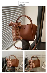 Close-up of brown leather bucket bag with silk scarf accent and logo detail