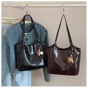 Detail of glossy patent leather tote bags in black and brown with baseball pendants