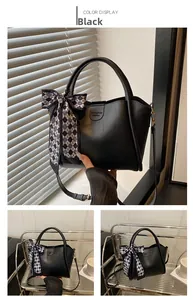 Detail of black leather bucket bag with checkered bow scarf and adjustable strap