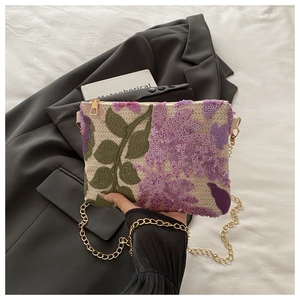 Detailed close-up of green leaf embroidery and purple sequins on woven shoulder bag