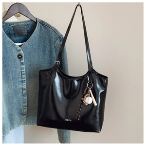 Detail of glossy black tote bag with fashion lettering and unique baseball charm
