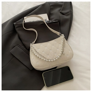 Détail de broderie florale sur sac beige matelassé avec double chaîne en perles et métal