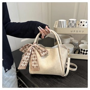 Detail of cream leather bucket bag featuring a decorative brown argyle silk scarf bow tie