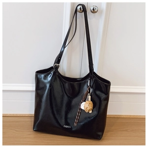 Detail of black faux leather tote with FASHION text and baseball sports charm