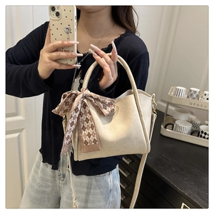 Mirror selfie showing a cream bucket bag with a brown checkered silk scarf detail