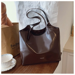 Detail of dark brown glossy leather tote bag with white Fashion lettering in cafe setting