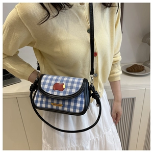 Détail d'un sac bandoulière à carreaux bleus avec écusson pomme rouge de style esthétique doux