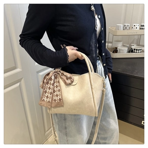 Detail of cream PU leather bucket bag featuring a decorative silk scarf and adjustable strap