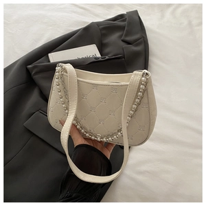 Détail d'un sac sous l'aisselle crème matelassé avec broderie papillon et perles
