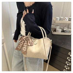 Detail of cream PU leather handbag with decorative silk scarf and adjustable strap