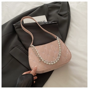 Détail d'un sac rose en cuir verni matelassé avec chaîne perlée et pendentif étoile