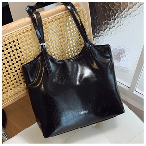 Detail of glossy wrinkled leather tote bag with FASHION text hanging on a chair