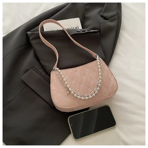Détail d'un sac à main rose matelassé avec chaîne en perles et pendentif étoile sur costume