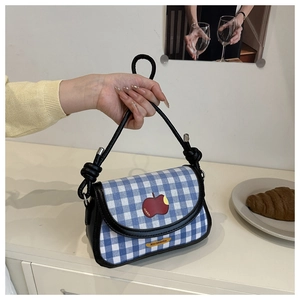 Détail du mini sac selle à carreaux avec broderie pomme et bandoulière en cuir noir