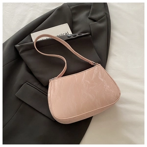 Détail du sac à bandoulière en cuir verni rose avec double chaîne sur un blazer