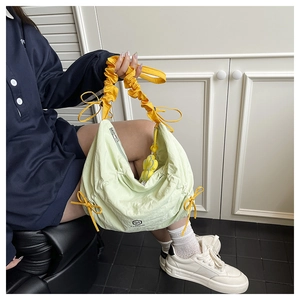 Detail of light green pleated handbag with yellow bow drawstring and brand lettering