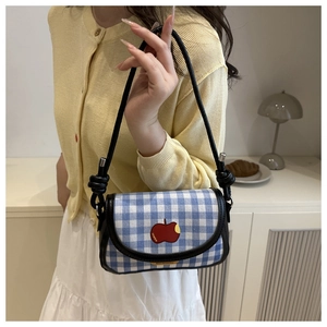 Détail du sac à carreaux bleus avec motif pomme rouge et bandoulière à nœud noir