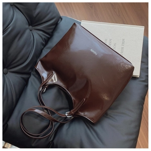 Detailed macro view of glossy dark brown leather tote bag with white fashion print