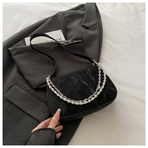 Détail du sac demi-lune noir avec chaîne argentée et décor de poignée en perles blanches