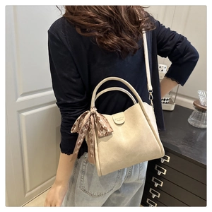 Detail of cream white leather bucket bag featuring a silk scarf and JINGPIN logo