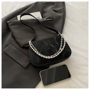 Détail du sac bandoulière en cuir noir matelassé avec double chaîne perle et métal