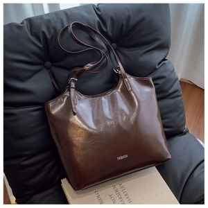 Detail of glossy brown tote bag with white FASHION lettering on a stylish chair