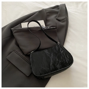Détail du sac à bandoulière noir à texture plissée avec anneaux en métal argenté