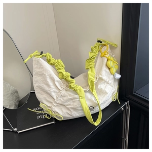 Detail of white nylon crescent bag with neon yellow scrunchie strap and flower charm