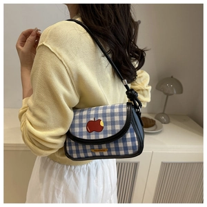Gros plan d'un sac à carreaux bleu et blanc avec écusson pomme rouge sur le mannequin