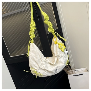 Detail view of nylon crescent bag with neon green ruffled strap and sunflower pendant