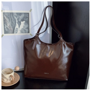 Detail of glossy dark brown tote bag with FASHION text in an elegant cafe setting