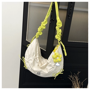 Detail of white nylon crescent bag with lime green ruched strap and sunflower charm