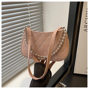 Detail of pink quilted baguette bag with pearl chain and bow embroidery patterns
